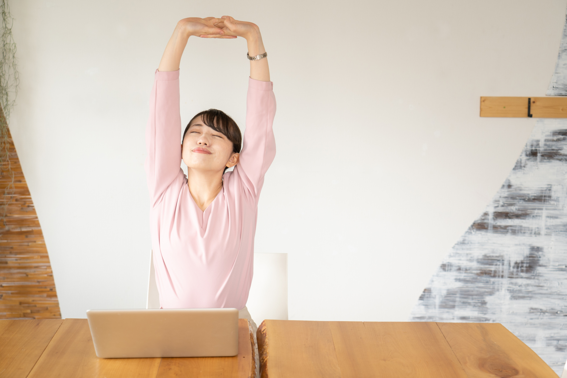 女性がノートパソコンの前でストレッチをしている様子